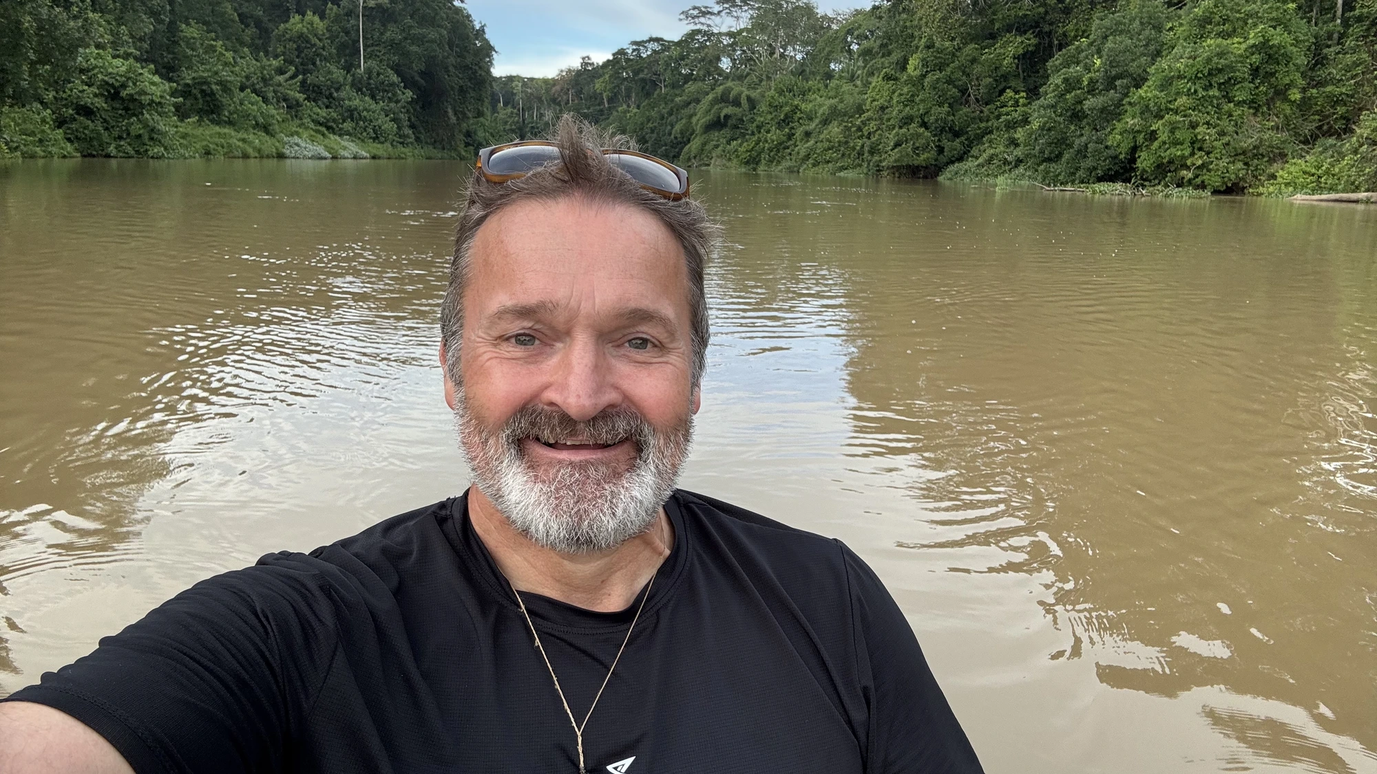 Jason Howard, founder of Echo Ridge Retreat, smiling by a river surrounded by forest